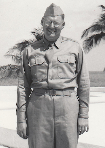 Army Air Force Pvt. Elmer Goll in Miami Florida in February 1943. Pvt. Goll wears the convertible collar khaki cotton shirt approved in 1941. This shirt was designed to maintain an acceptable military appearance with its collar open without a necktie or closed with a necktie. The sports collar made wear in the field more comfortable where a necktie was not required. Identification of this shirt is made easy by its lack of a front button placket. Note the dished zinc waistband button visible just underneath the nonregulation solid belt buckle. Dished buttons were a feature of early production specification 6‐254 khaki trousers. Army Air Force Pvt. Elmer Goll in Miami Florida in February 1943. Pvt. Goll wears the convertible collar khaki cotton shirt approved in 1941. This shirt was designed to maintain an acceptable military appearance with its collar open without a necktie or closed with a necktie. The sports collar made wear in the field more comfortable where a necktie was not required. Identification of this shirt is made easy by its lack of a front button placket. Note the dished zinc waistband button visible just underneath the nonregulation solid belt buckle. Dished buttons were a feature of early production specification 6‐254 khaki trousers.
