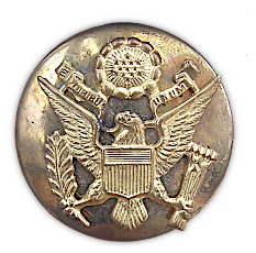 Close‐up view of the enlisted man's gilt service cap insignia from the khaki service cap shown to the left. The badge was affixed to the front of the cap by way of a threaded post and nut which passed through the cover and riser. Army regulations of 1941 specified that the coat of arms of the United States be a separate piece and be superimposed on a disk 1½‐inches in diameter. WW2 cap badges were composed of a variety of materials including brass, gold washed metal alloys, and plastic. Some economy versions were stamped or molded in one piece. Close‐up view of the enlisted man's gilt service cap insignia from the khaki service cap shown to the left. The badge was affixed to the front of the cap by way of a threaded post and nut which passed through the cover and riser. Army regulations of 1941 specified that the coat of arms of the United States be a separate piece and be superimposed on a disk 1½‐inches in diameter. WW2 cap badges were composed of a variety of materials including brass, gold washed metal alloys, and plastic. Some economy versions were stamped or molded in one piece.