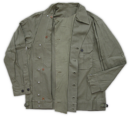 Herringbone Twill Jacket (Modified).  In the spring of 1942, on the recommendation of the Chemical Warfare Board, the Army began adding gas protective features to uniforms. Here it can be seen that a flap has been added behind the front button closure of this jacket.  This was to prevent blistering agents from passing through the opening and contacting the skin.  Another modification was the addition of buttons behind the collar to attach a protective hood. Garments were labeled "special" to indicate these modifications were present. To be effective, special garments had to be immersed in a solution to make the fabric impermeable to the chemical irritant.  By the summer of 1943 special features were standard on all new herringbone twill suits.  When this occurred, many older garments, like the one shown here, were retrofitted to comply with the new standard.