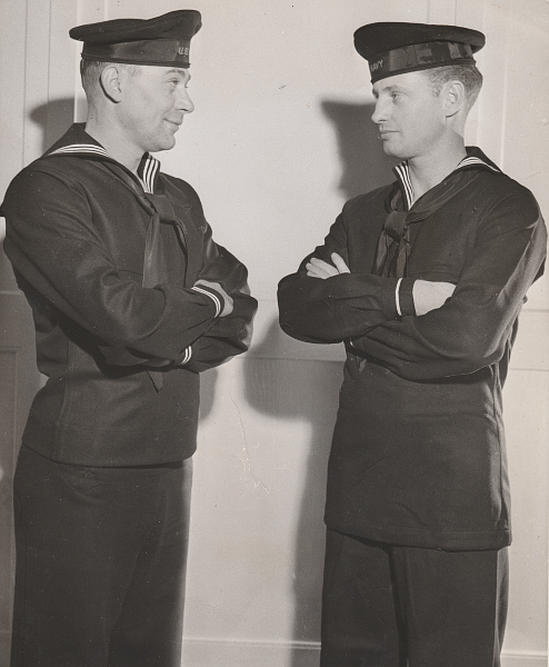 This photo, taken at the Naval Clothing Depot, Brooklyn, NY on 19 December 1943, shows two sailors modeling the new (left) and old (right) dress blue jumper.  The new jumper was six inches shorter and was intended to help conserve fabric and improve the appearance of the uniform. Note the location of the skirt hem seam on the new jumper. A generous amount of excess material was provided that could be let down to assure proper fit.  The old jumper is being worn fully extended for comparative purposes.   When worn properly, the old jumper had a draw string in a narrow channel at the bottom hem that was tightened around the waist with the remaining material then bloused over the hips. Note that the new jumper has two cuff stripes and the old jumper one.  As an additional point of interest, both men happen to be wearing shoe-string style neckerchiefs. (Associated Press Photo)
