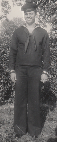 This 1944 photo shows a young Second Class Seaman wearing his Dress Blue A uniform while visiting home.   His jumper is the Pre-1944 type and is bloused over at the waist. It can be observed that there are two stripes on the cuffs of his jumper and his neckerchief is rolled as prescribed by regulation. Trouser bottoms hang loose when worn with low-quarter shoes.